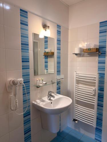 a white bathroom with a sink and a mirror at Penzion VV SUN - REOS in Hodonín