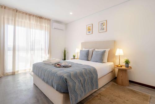 a white bedroom with a large bed and a window at Bright & Spacious Flat with Balcony by HostWise in São Mamede de Infesta