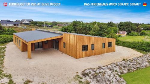 a large wooden building on top of a field at Eksklusivt Luksusferiehus Med Pool Sj455 in Harboør