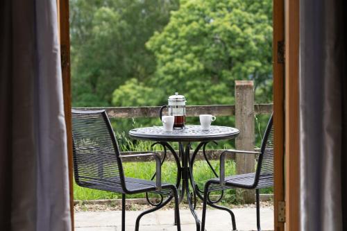 a table with two chairs and two cups on a patio at Pretty Wood Cottage Quiet Cottage in Private Meadow in Eyam