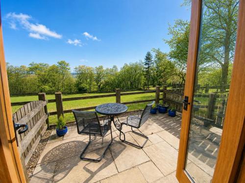 a patio with a table and chairs and a fence at Pretty Wood Cottage Quiet Cottage in Private Meadow in Eyam