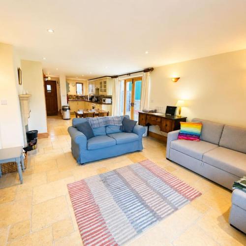 a living room with two blue couches and a rug at Riley Wood Cottage Peaceful Cottage, Views & Walks in Eyam