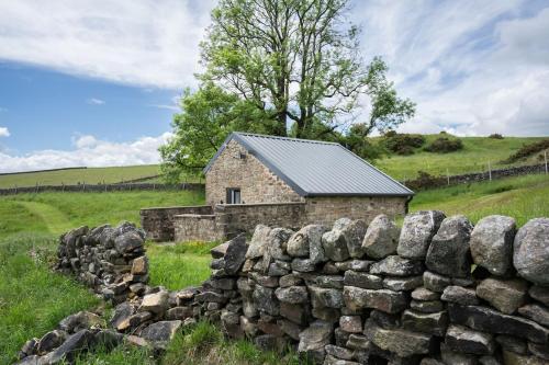 an old stone house behind a stone wall at Barn Peaceful Stay with Far-Reaching Views in Eyam