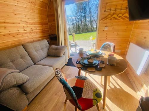 a living room with a couch and a table at Kestrel Cabin Quiet Woodland Cabin & Nature in Eyam