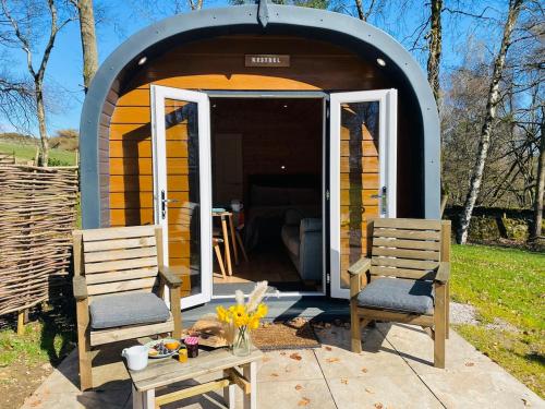 two chairs sitting in front of a tiny house at Kestrel Cabin Quiet Woodland Cabin & Nature in Eyam
