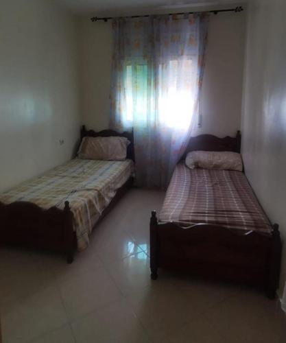 two beds sitting in a room with a window at Martil calm apartment in Martil