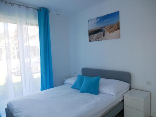 a bed with blue pillows on it in a room with a window at Wisełka Apartamenty Sea & Lake in Wisełka