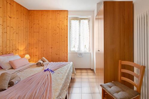 a bedroom with a bed and a chair and a window at Casa Heidi in Castello Tesino