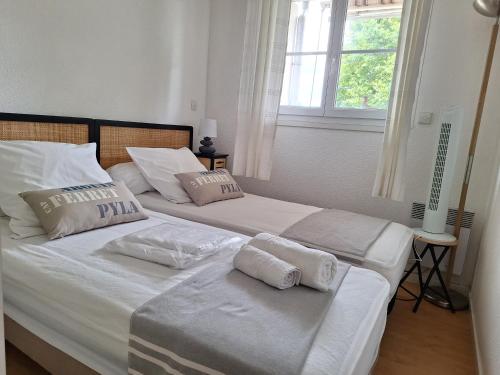 two beds in a bedroom with white sheets and pillows at Le Pacha in Andernos-les-Bains