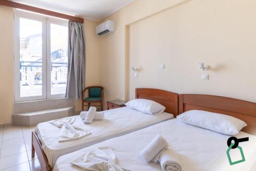 two beds in a room with a window at Hotiday Zakynthos Argassi in Zakynthos