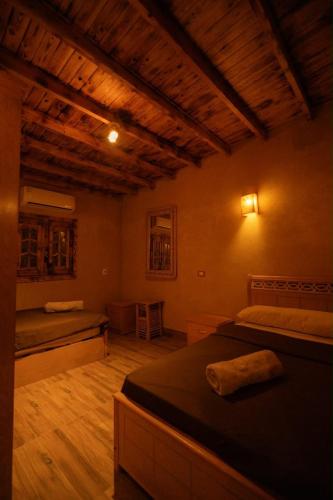 a bedroom with two beds and a wooden ceiling at Ayur Lodge Siwa Oasis in Siwa