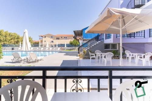 a patio with chairs and an umbrella and a pool at Hotiday Zakynthos Argassi in Zakynthos