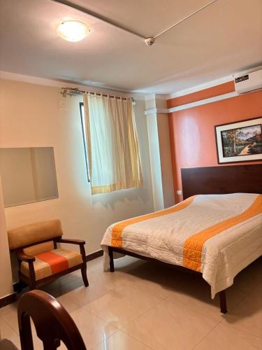 a bedroom with a bed and a chair and a window at Sol Del Sur Hotel in Huaquillas