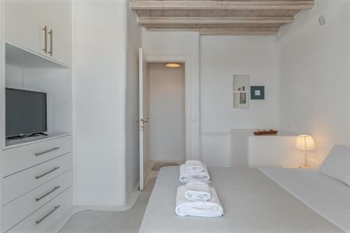 a white room with towels on a bed and a tv at Villa blaue Welle in Kalo Livadi