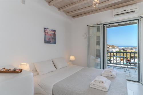 a white bedroom with a bed and a balcony at Villa blaue Welle in Kalo Livadi