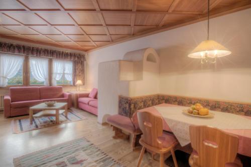 un soggiorno con un tavolo e un divano di Residence Dolomieu a San Cassiano
