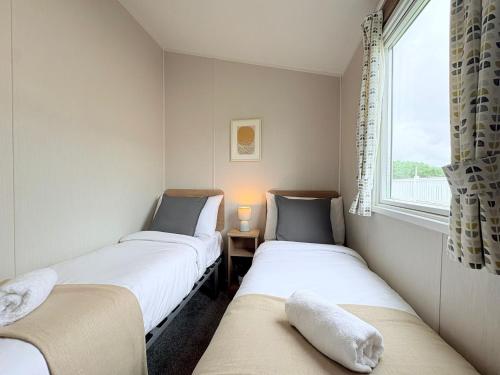 two twin beds in a room with a window at Coastal Escape in Heysham