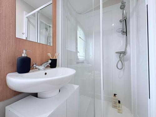 a white bathroom with a sink and a shower at Coastal Escape in Heysham