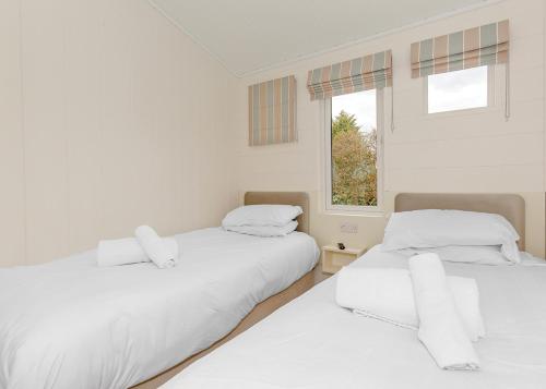 two white beds in a room with a window at Talacre Beach Resort in Talacre