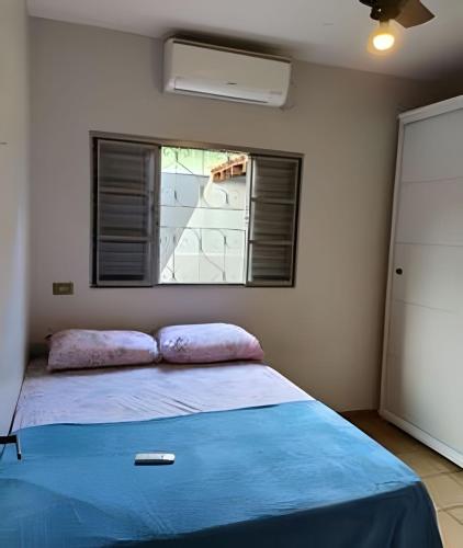 a bedroom with a bed with a blue blanket and a window at Dourados Guest Flat House in Dourados