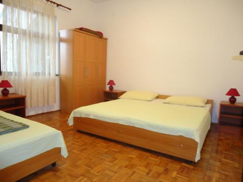 ein Schlafzimmer mit zwei Betten und einem großen Fenster in der Unterkunft Apartments Vrša in Seline