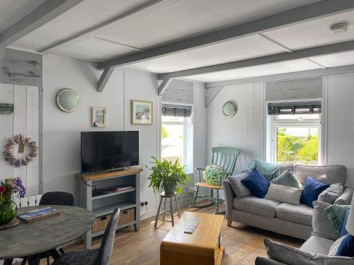 a living room with a couch and a tv at Summers Beach View in Saint Mawes