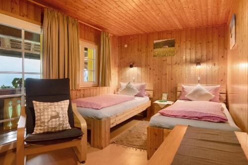 a bedroom with two beds and a chair and a window at Reesbauernhof - Fewo Abendrot in Oberried