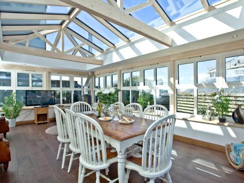 a dining room with a wooden table and white chairs at Headland Views in Newquay