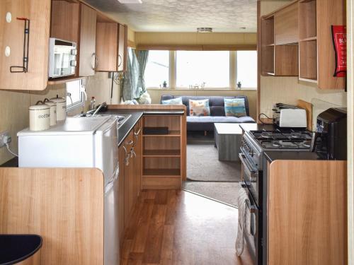 a small kitchen with a stove and a living room at Beech Walk 45 - Ukc9406 in Exmouth