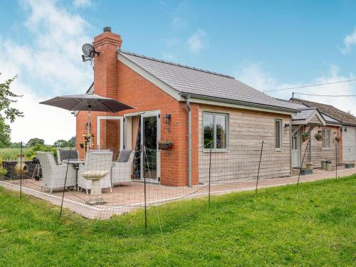 a small brick house with a patio with an umbrella at Violet Cottage in Hereford
