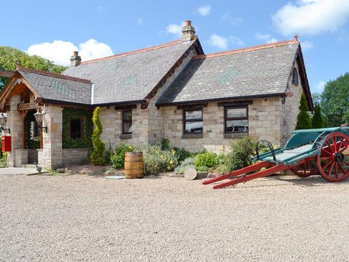 a stone house with a red wagon in front of it at Tennox Boathouse - Ukc4438 in Kilbirnie
