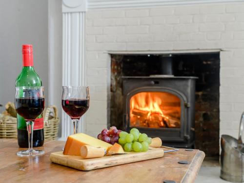 a table with two glasses of wine and cheese and a fireplace at Colveston Manor in Cranwich