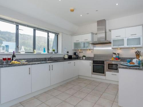 a large kitchen with white cabinets and windows at Sand Dunes in Westward Ho