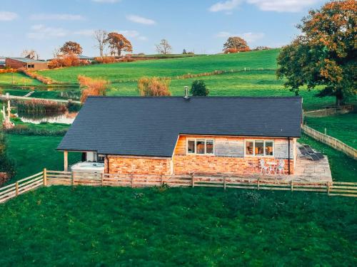 a log home with a black roof on a green field at The Cwtch - Os7 in Newtown
