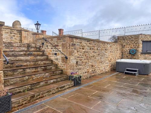 a brick wall with stairs next to a stone wall at Ghyll Cottage - Uk51667 in Leyburn