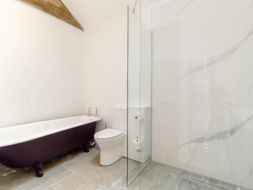 a bathroom with a tub and a toilet and a glass shower at Loch Farm Stables in Watton