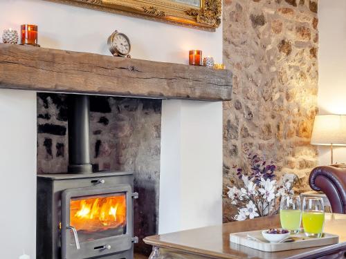 a wood stove in a living room with a table with drinks at West House in Wooler
