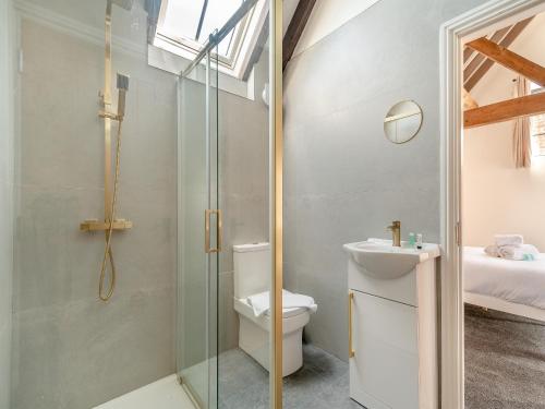 a bathroom with a toilet and a glass shower at Corley Rocks Barn - Uk45939 in Corley