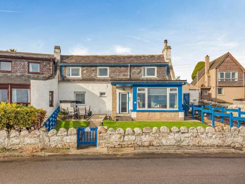 a house with a blue fence in front of it at Roggle Roich in Hilton of Cadboll