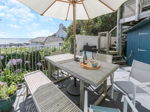 a table and chairs with an umbrella on a patio at Dolphins Reach in Saint Mawes