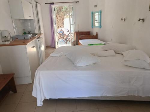 a bedroom with two beds and a kitchen with a window at Sifnos studio 5 in Sifnos