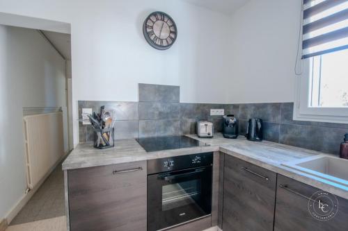 a kitchen with a sink and a clock on the wall at Maison Le Damier - Proche Center Parcs et Lamotte Beuvron - 3 chambres in La Ferté-Saint-Aubin