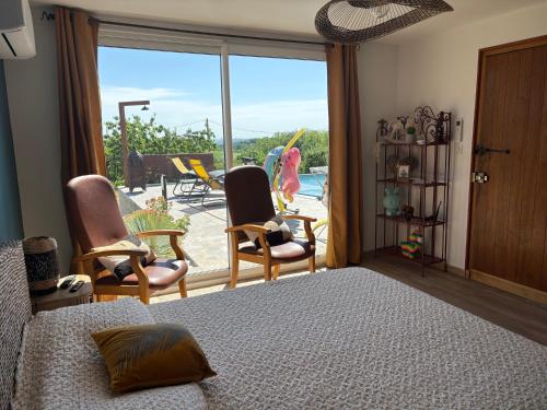 a bedroom with a bed and chairs and a balcony at Les vergers d'Anjoy in Montesquieu