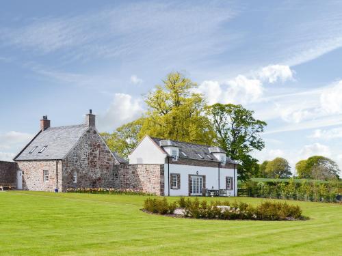 an old stone house on a green lawn at Grieve's Cottage - Uk11107 in Montrose