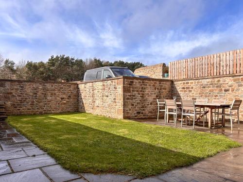 a patio with a table and chairs next to a brick wall at Stable Cottage - Uk51669 in Leyburn