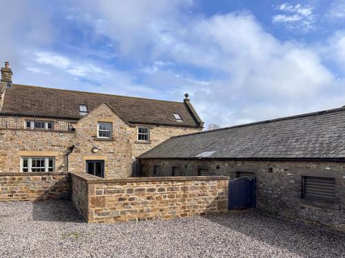 an old stone building with a stone wall in front of it at Stable Cottage - Uk51669 in Leyburn