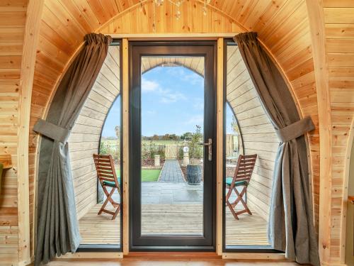 an arched glass door in a wooden house with two chairs at The Hive - Uk45565 in Longford