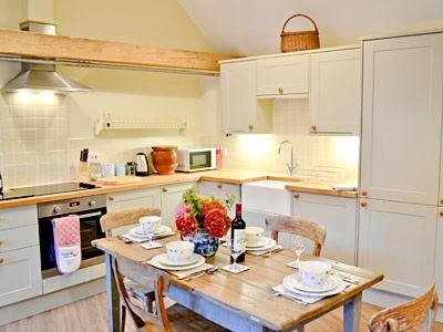 a kitchen with a wooden table with chairs and a table sidx sidx sidx at Ox Lodge Barn - Pqqw in Battle