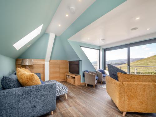 a living room with blue walls and chairs and windows at Blodfryn in Llandudno Junction