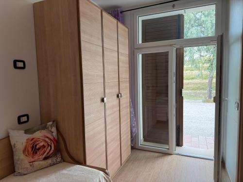 a bedroom with a large wooden cabinet and a sliding glass door at Le Essenze - Agriturismo con vista in Cesena